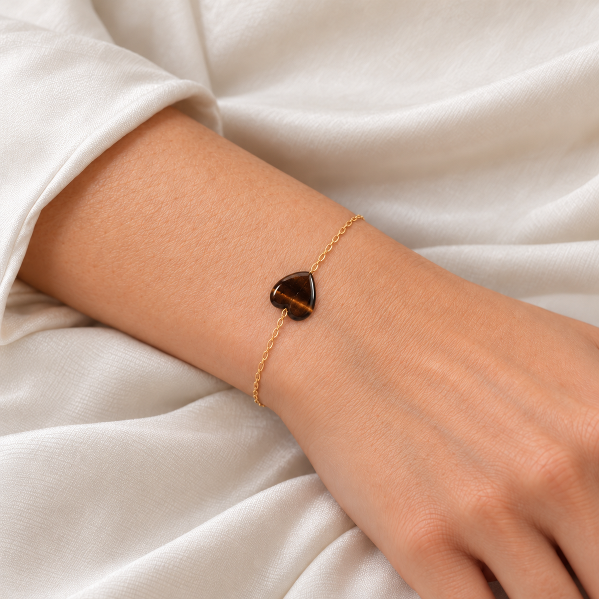 Harmony Touch Armband mit feiner goldfarbener Kette und dunkelbraunem Tigerauge-Herz am Handgelenk.