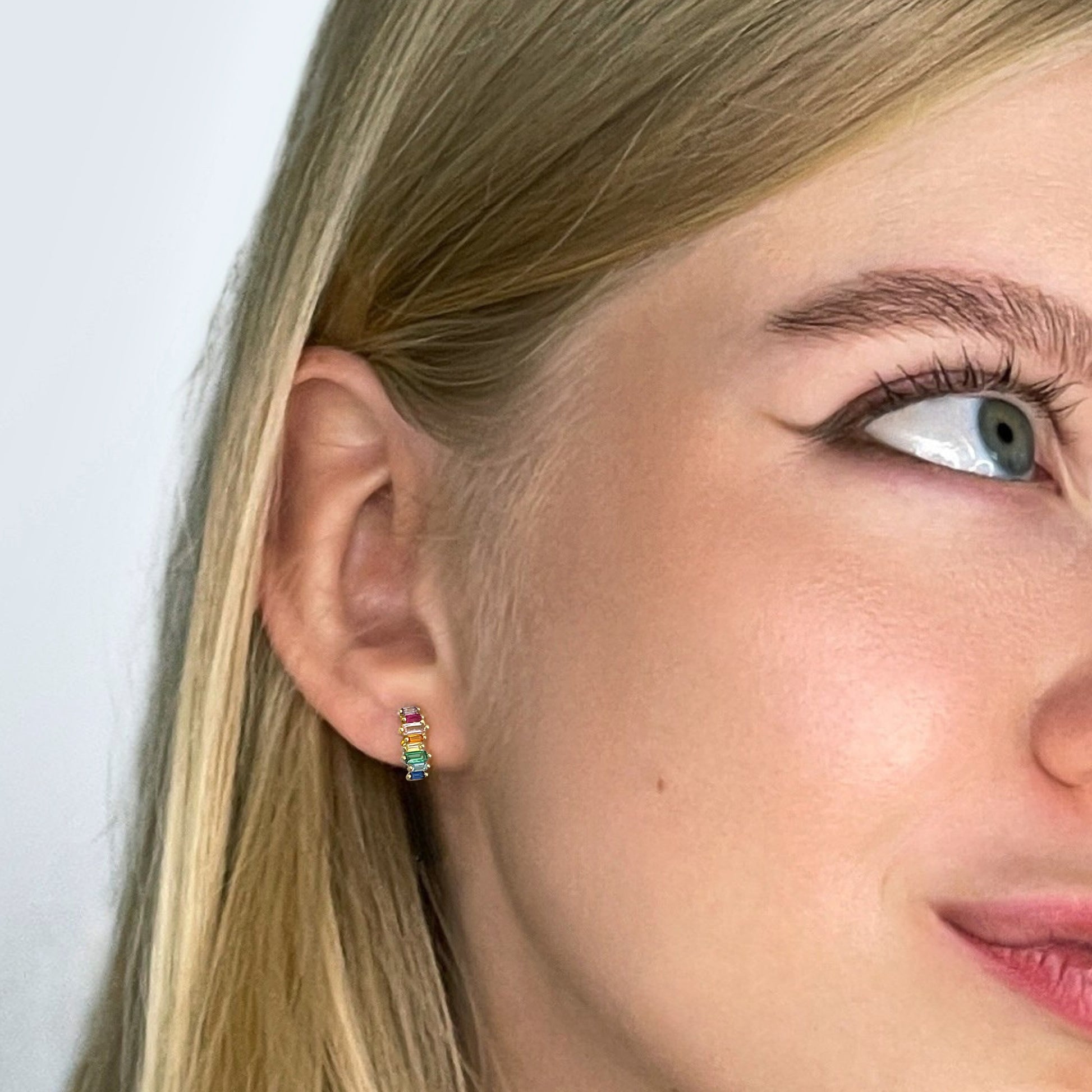 Nahaufnahme eines Models mit den kleinen Ohrsteckern Color 22 aus vergoldetem Edelstahl und bunten rechteckigen Zirkonia-Steinen