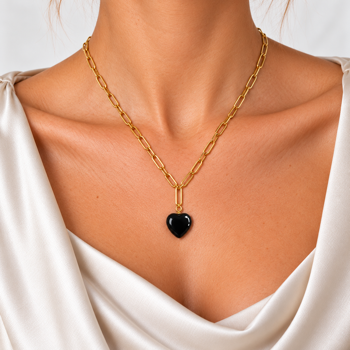 Nahaufnahme der Bold Harmony Halskette mit goldfarbenen länglichen Gliedern und schwarzem Achat-Herz.