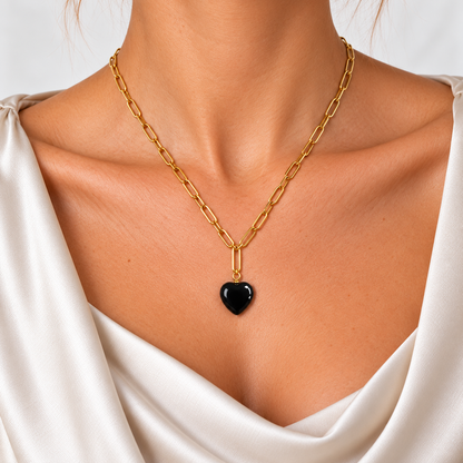 Nahaufnahme der Bold Harmony Halskette mit goldfarbenen länglichen Gliedern und schwarzem Achat-Herz.